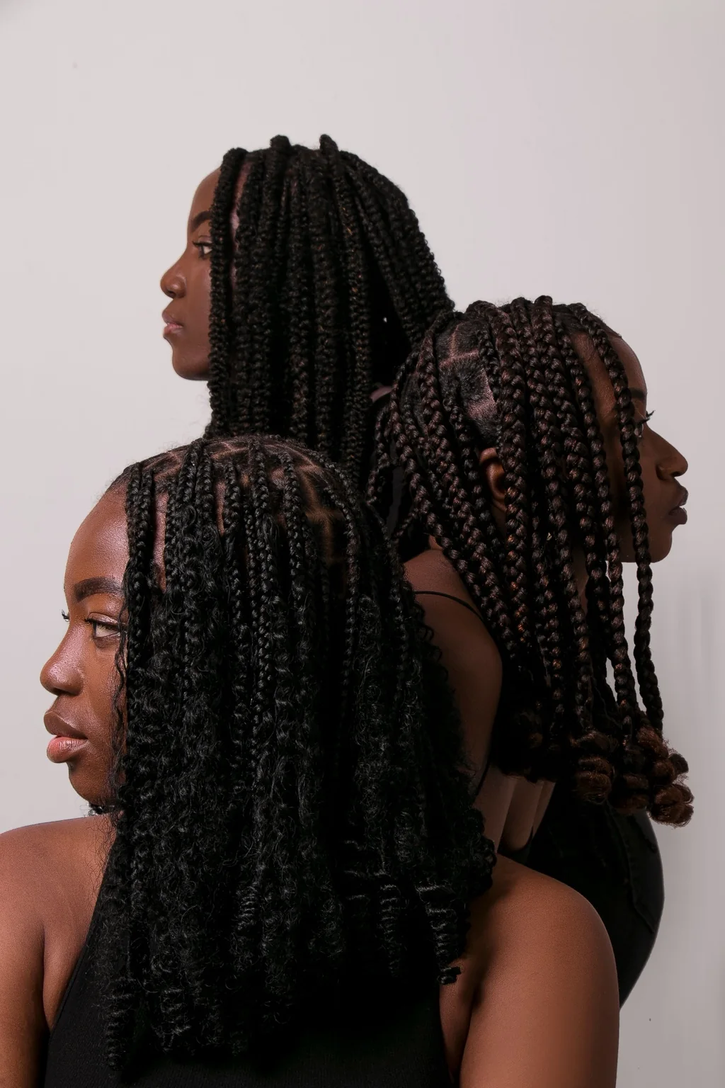 Three women with intricate braids photographed against a neutral backdrop